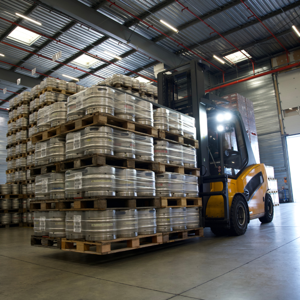 Chariot élévateur en pleine opération de manutention de palettes de fûts de bière dans l'entrepôt de Jung Logistique.