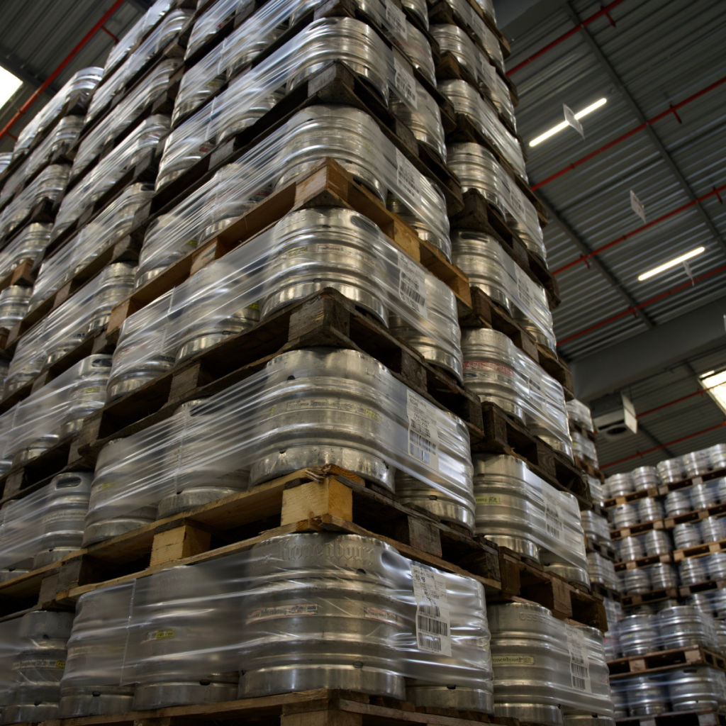 Piles de palettes de fûts de bière filmées et stockées en hauteur dans l'entrepôt logistique d’Obernai.