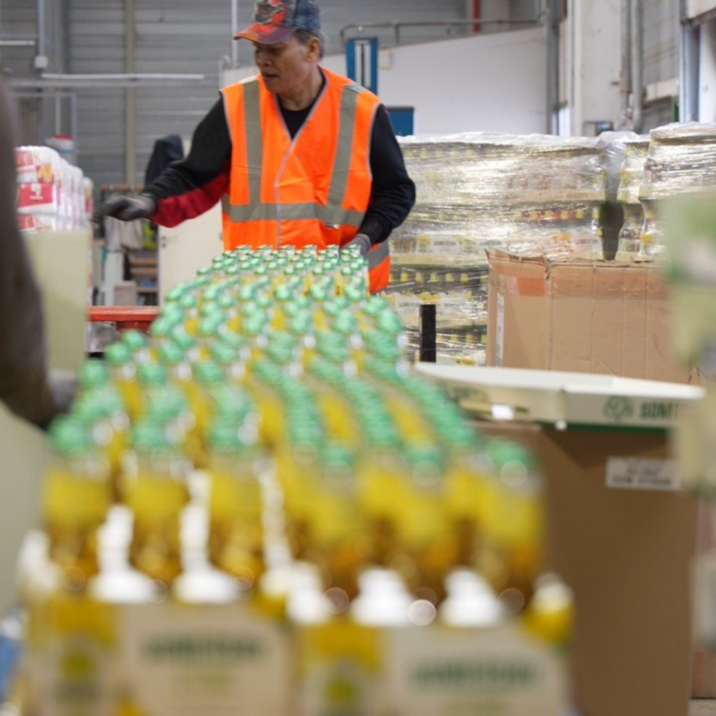 Un préparateur Jung Logistique travaille sur une ligne de co-packing de bouteilles dans un entrepôt.