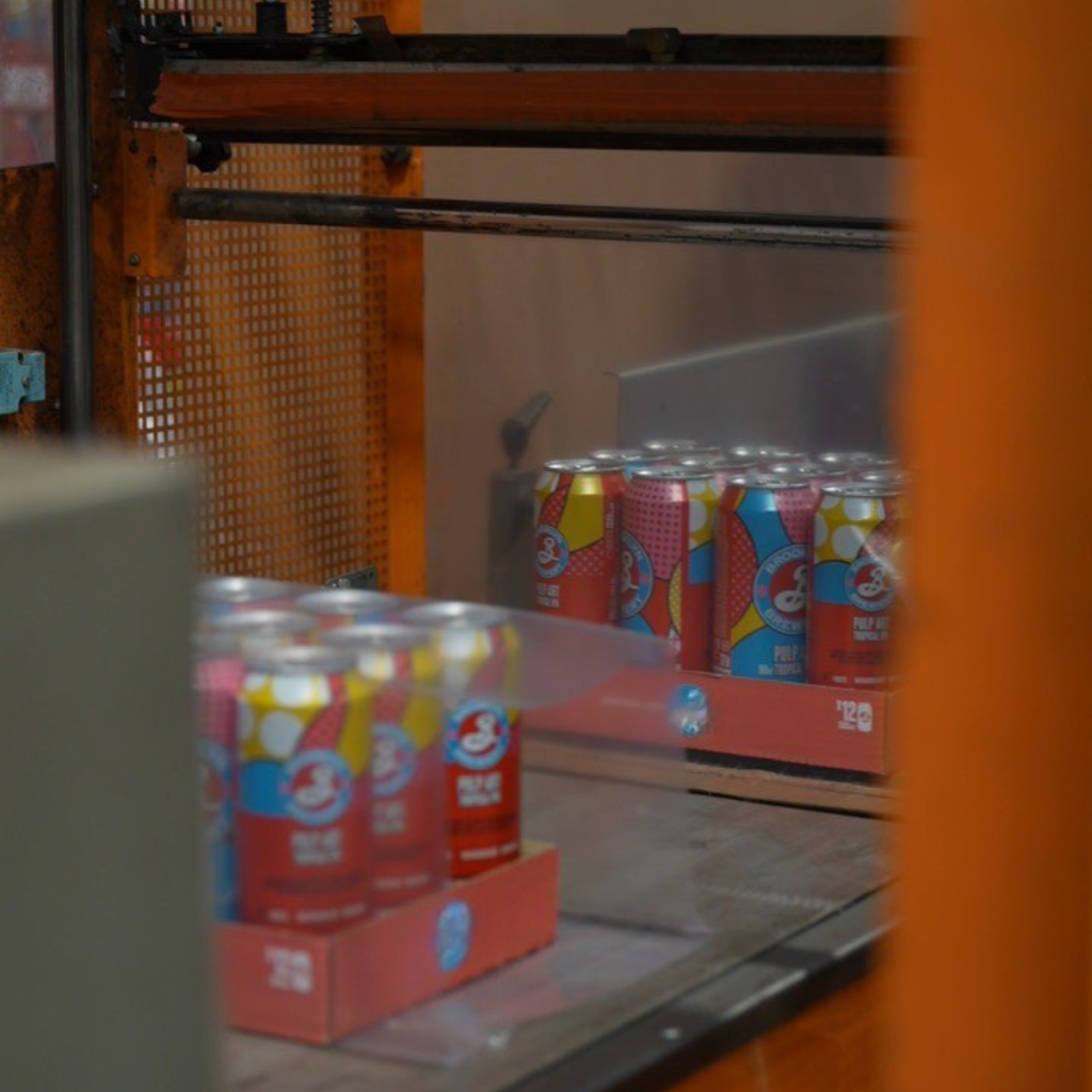 Packs de canettes de boisson conditionnés sur une ligne de co-packing automatisée dans un entrepôt Jung Logistique.